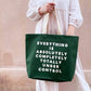 Person holding a green tote bag with text against a beige wall