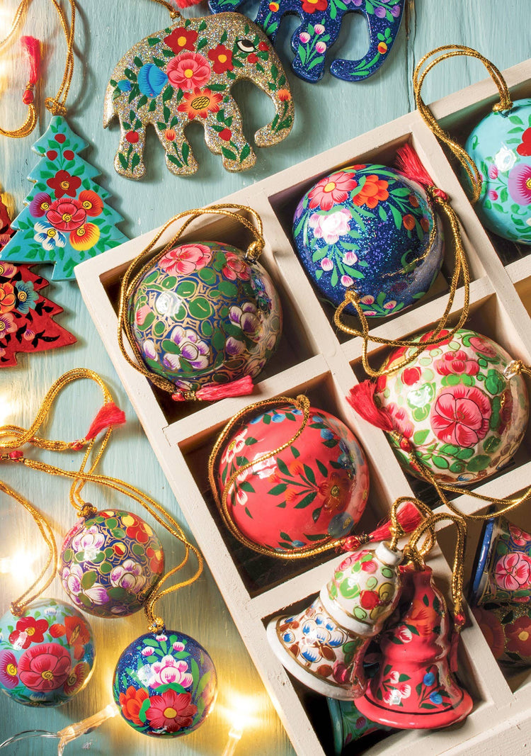 Colorful floral-patterned Christmas ornaments in a box with string lights.