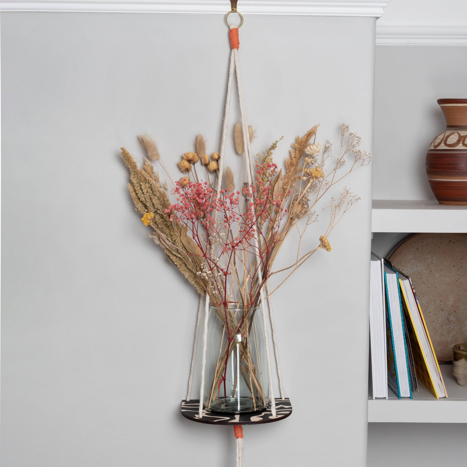 Hanging macrame plant shelf that rests neatly against the wall. Bold and graphic black and white print with natural white macrame twine and brass plated hoops. Made in England. 