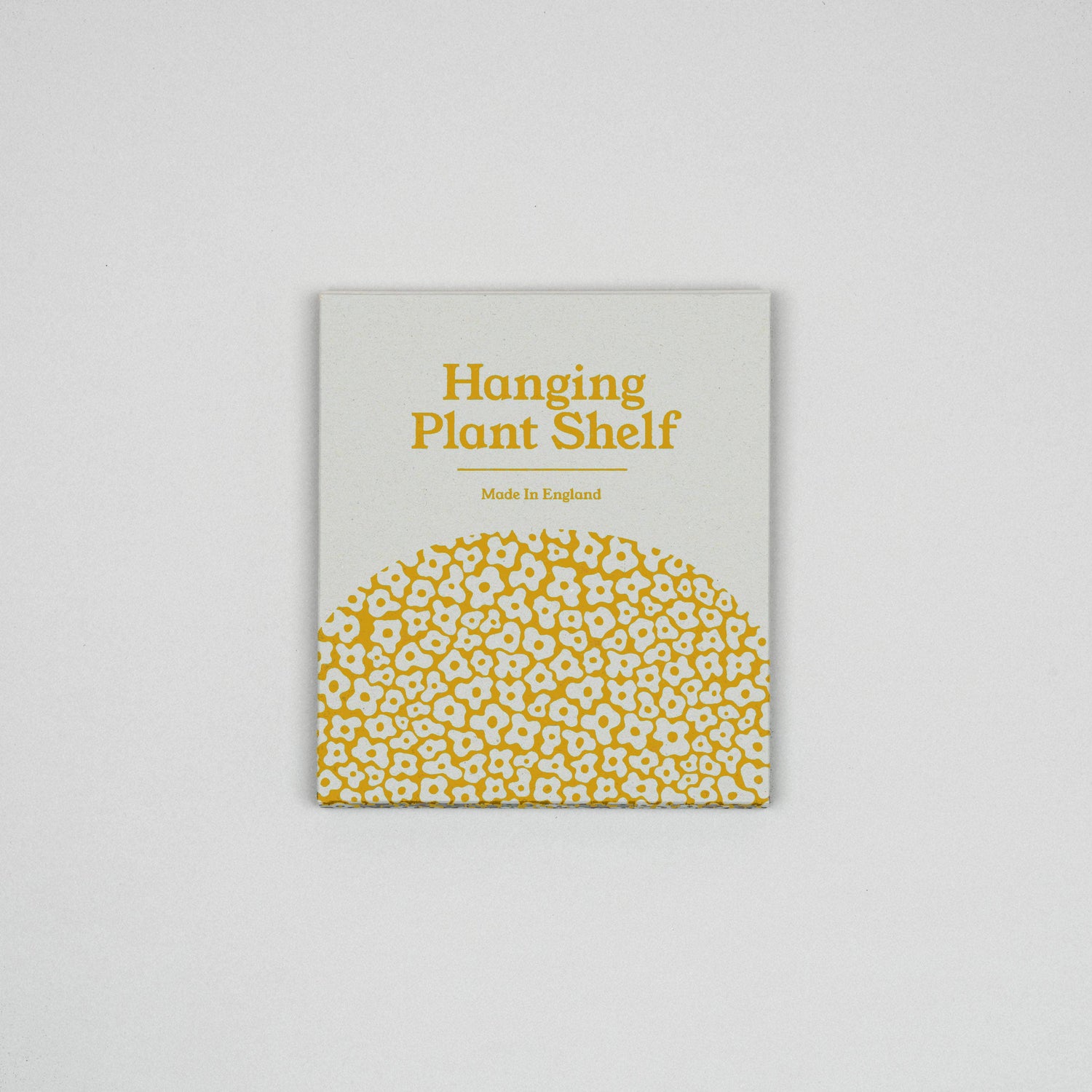 Hanging macrame plant shelf that rests nearly against the wall. Yellow and white floral print with colourful twine, brass plated hoops and crimp bars. Made in England. 