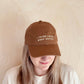Person Wearing a Cotton Baseball Cap with ‘I Think I Need More Coffee’ Text on a white Background