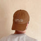 Person Wearing a Cotton Baseball Cap with ‘I Think I Need More Coffee’ Text on a White Background