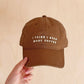 Cotton Baseball Cap with ‘I Think I Need More Coffee’ Text on a Neutral Background