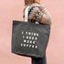 Person Carrying a Grey Tote Bag with ‘I Think I Need More Coffee’ Text on a Pink Background