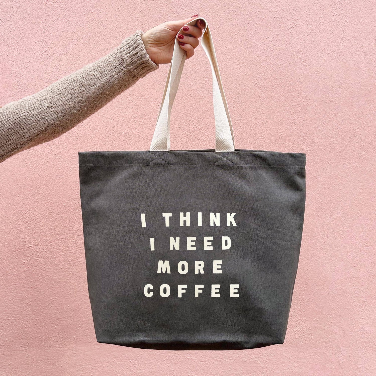 Grey Tote Bag with ‘I Think I Need More Coffee’ Text on a Pink Background