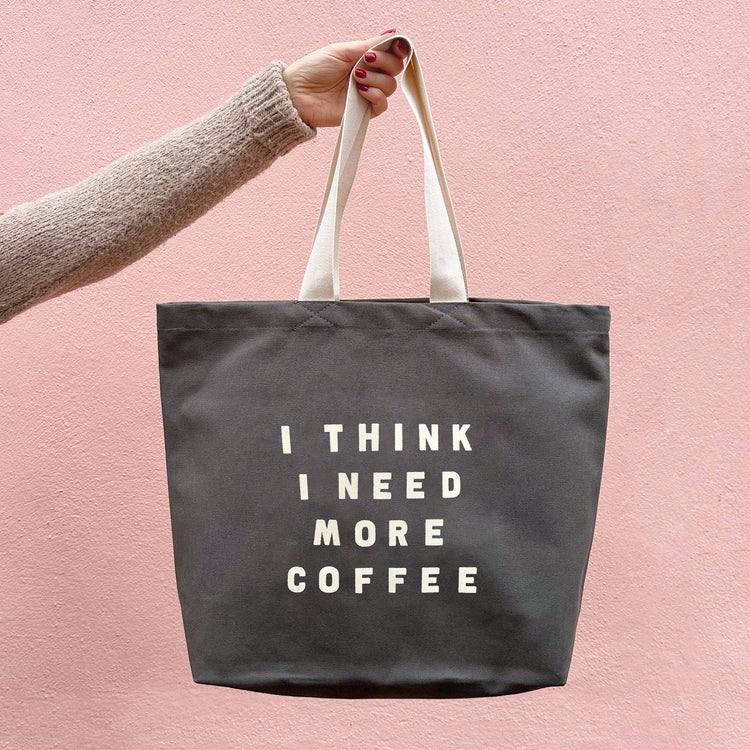 Grey Tote Bag with ‘I Think I Need More Coffee’ Text on a Pink Background