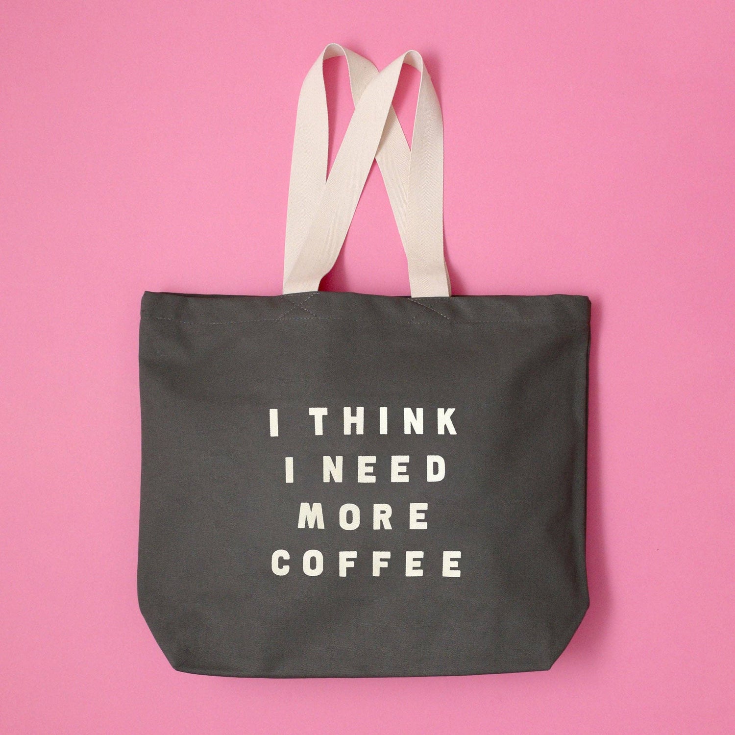 Grey Tote Bag with ‘I Think I Need More Coffee’ Text on a Pink Background