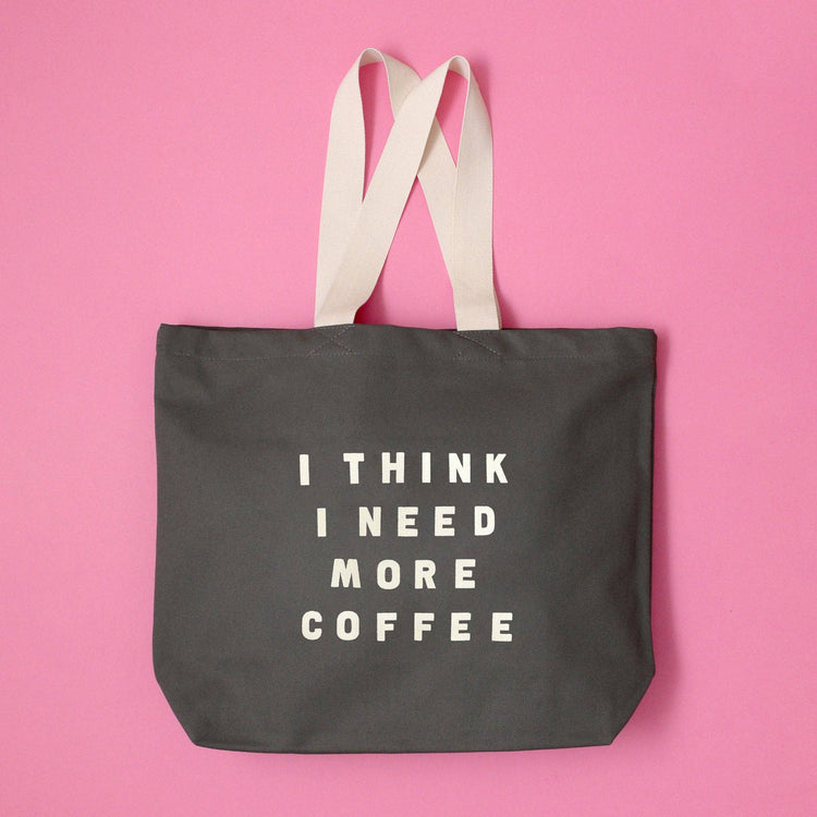 Grey Tote Bag with ‘I Think I Need More Coffee’ Text on a Pink Background