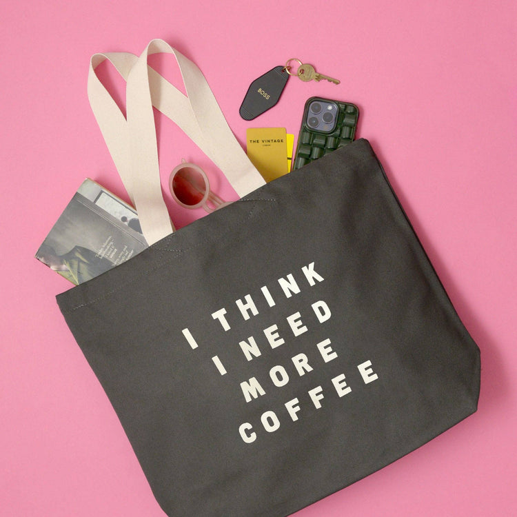 Grey Tote Bag with ‘I Think I Need More Coffee’ Text on a Pink Background