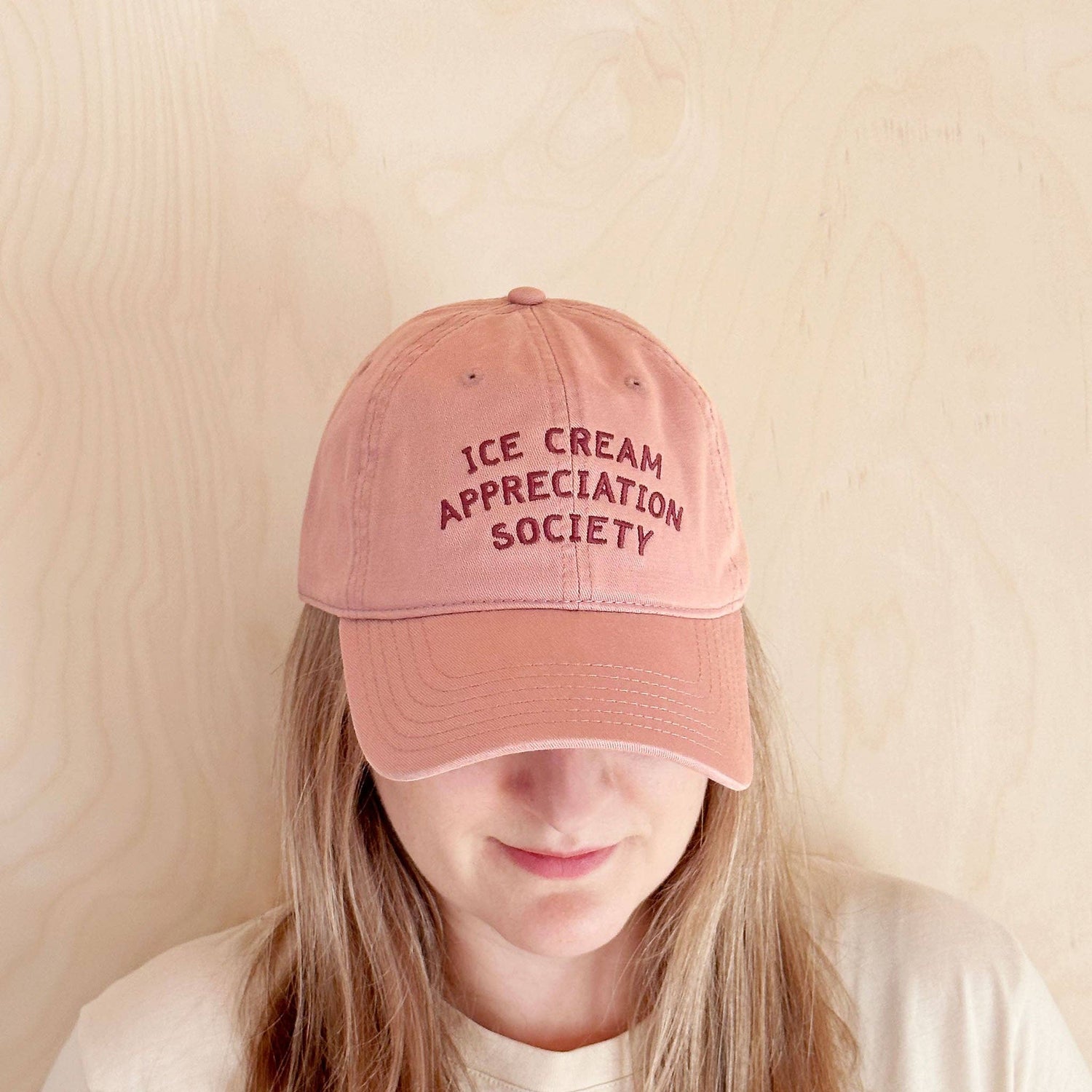 Person Wearing a Dusty Rose Cotton Baseball Cap with ‘Ice Cream Appreciation Society’ Text on a white Background
