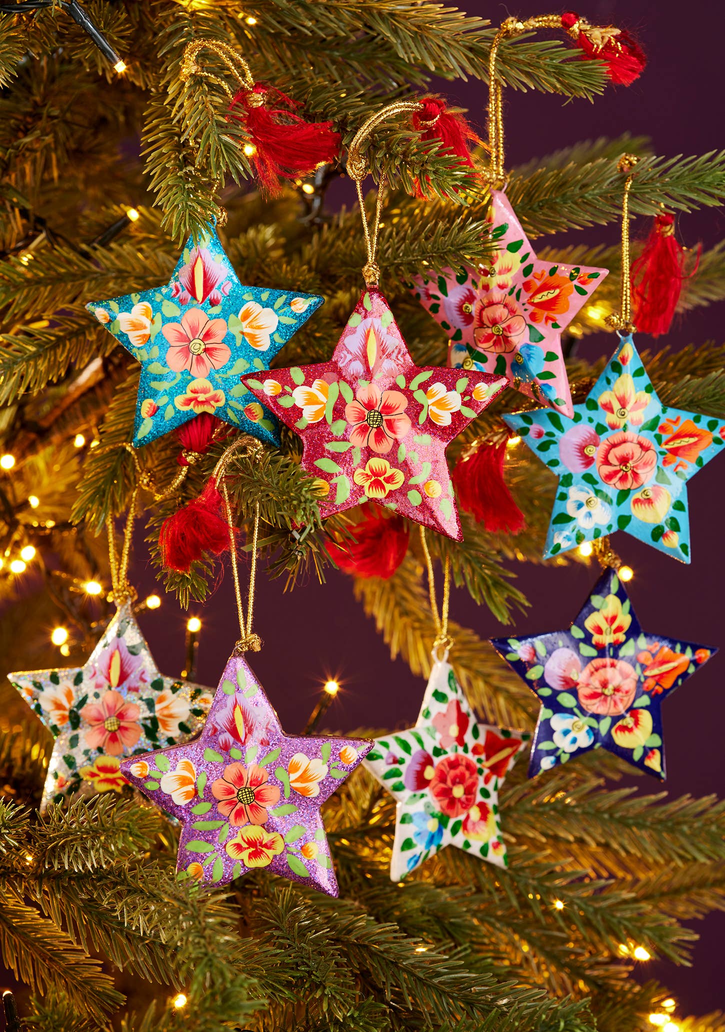 Colorful star-shaped Christmas ornaments on a tree with lights.