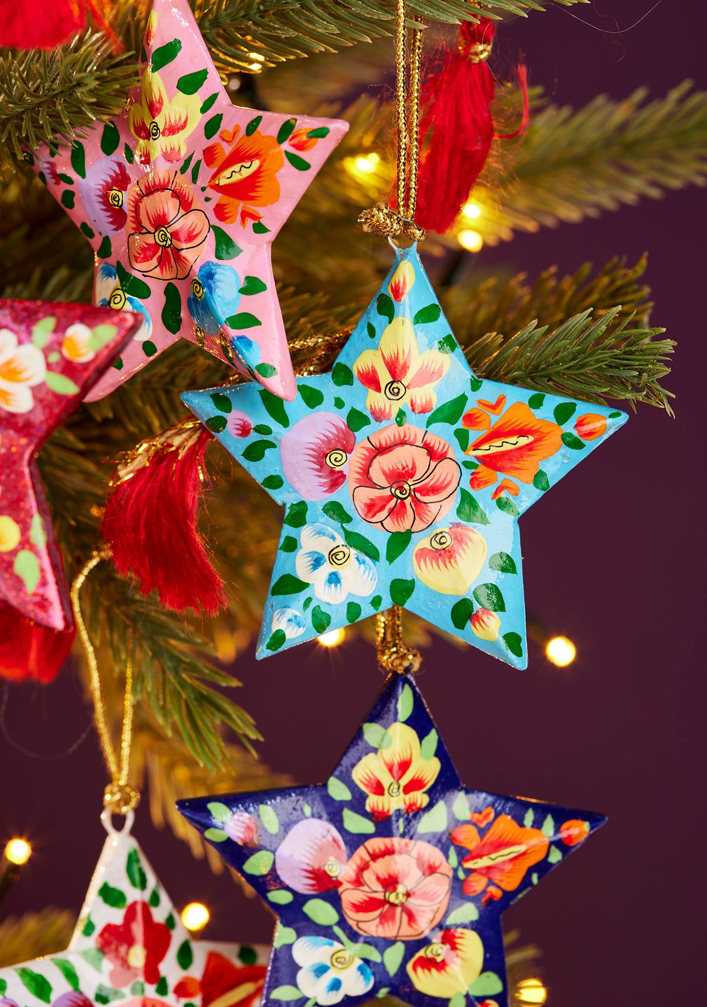 Colorful star-shaped Christmas ornaments on a tree with a dark purple background.