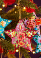 Decorative star ornaments with floral patterns hanging on a Christmas tree.