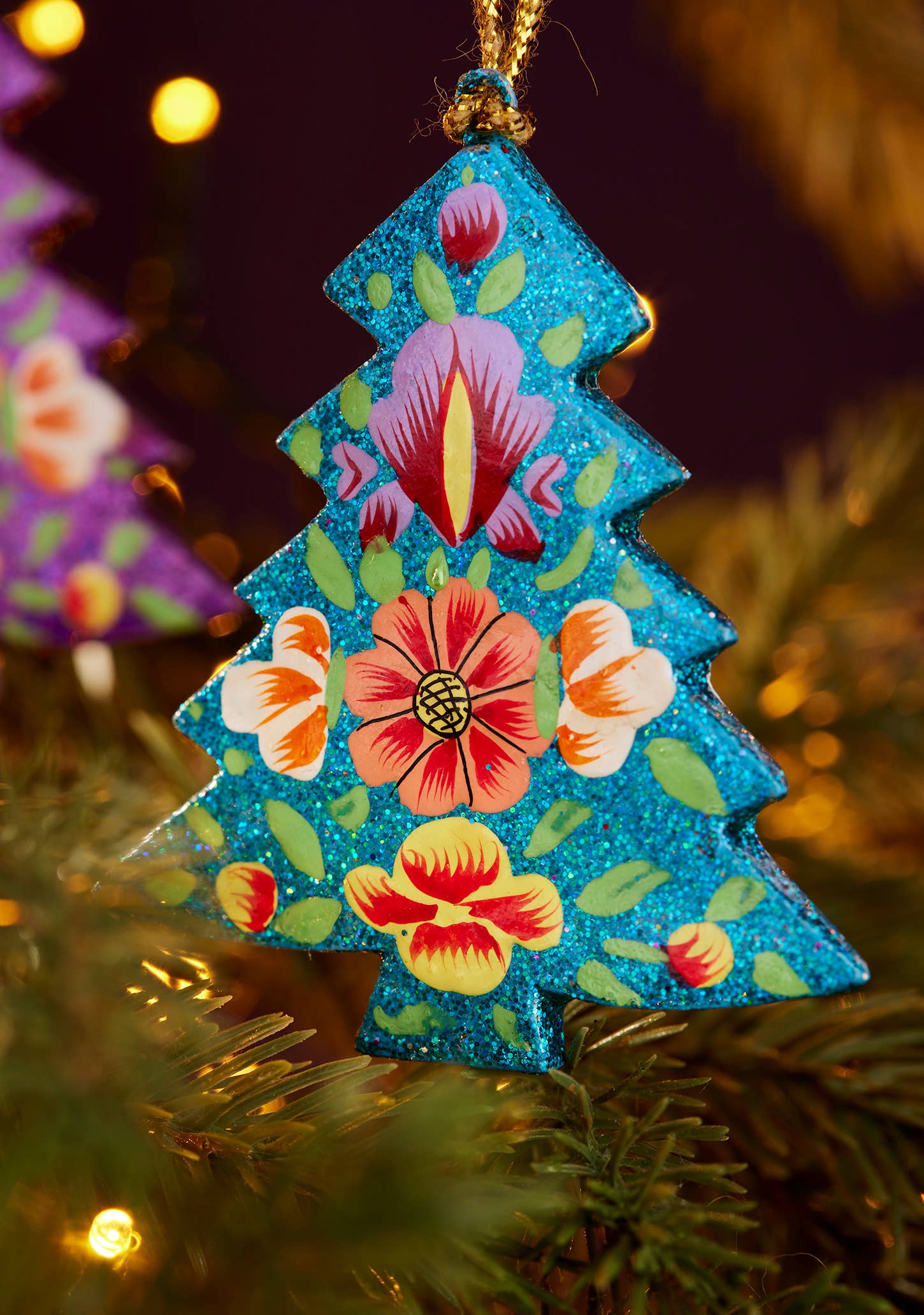 Decorative Christmas tree ornament with floral patterns hanging on a tree.