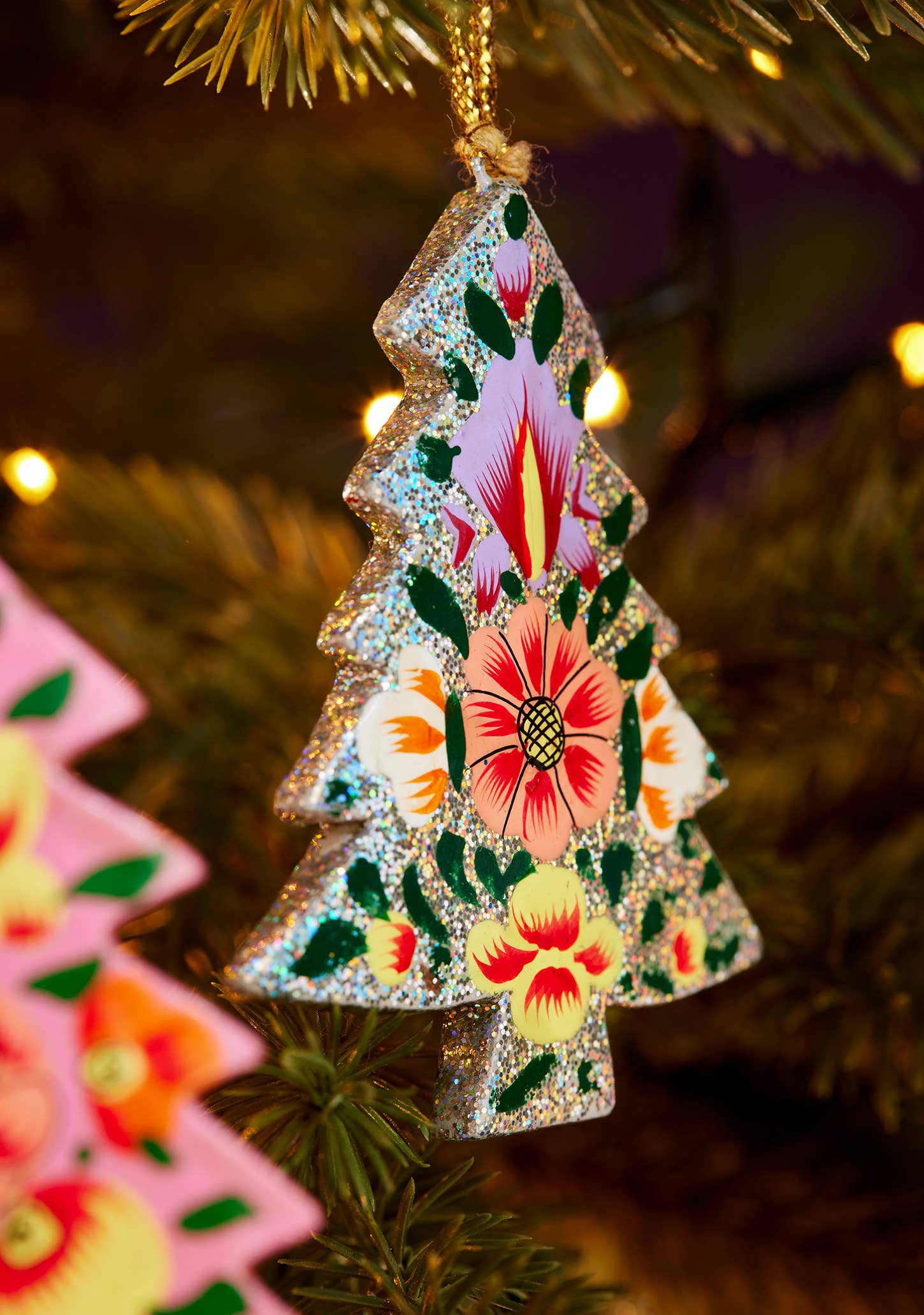 Decorative Christmas tree ornament with floral patterns hanging on a tree.