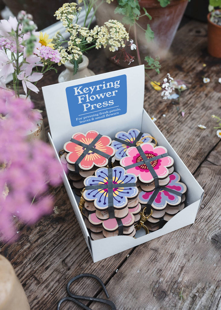Attached to a lobster-claw Keyring, a pocket flower press that is a perfect size to press and dry flowers on the go. Flower-shaped in pink qnd yellow.. Strong elastic bands, 5 sheets of corrugated card and 8 sheets of sugar paper to ensure good pressing. 