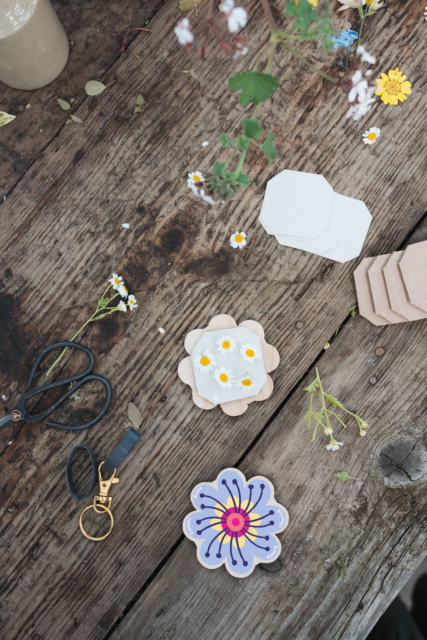 Attached to a lobster-claw Keyring, a pocket flower press that is a perfect size to press and dry flowers on the go. Flower-shaped in pink qnd yellow.. Strong elastic bands, 5 sheets of corrugated card and 8 sheets of sugar paper to ensure good pressing. 