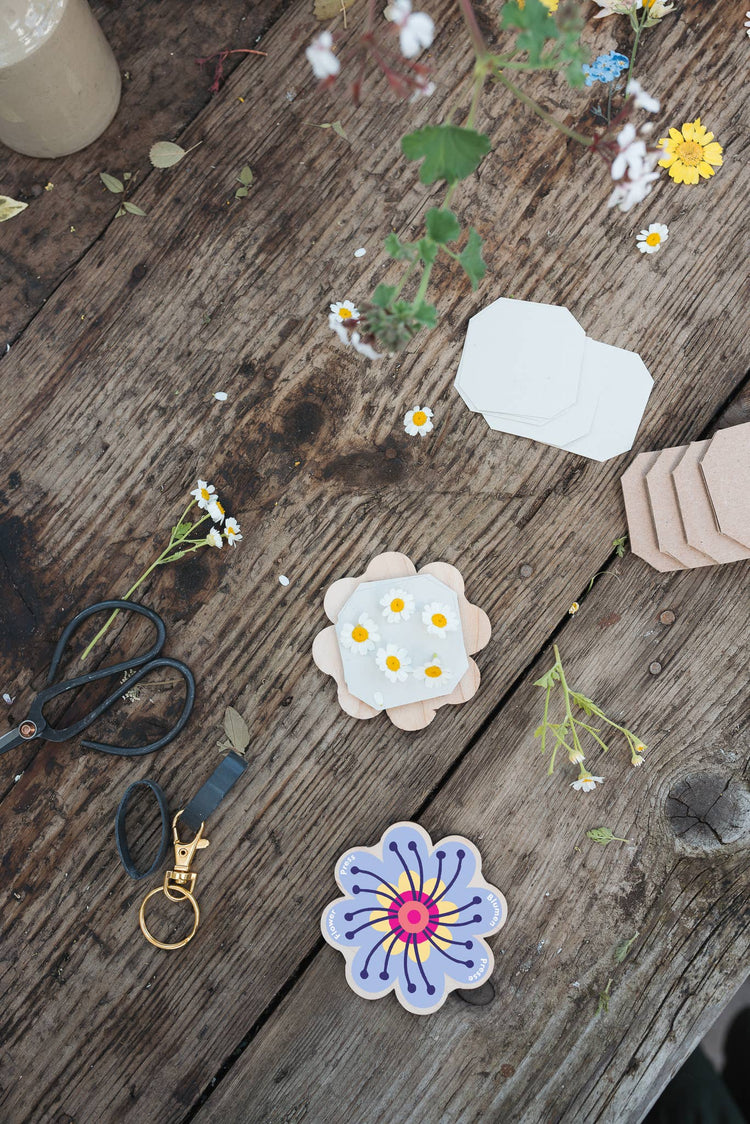 Attached to a lobster-claw Keyring, a pocket flower press that is a perfect size to press and dry flowers on the go. Flower-shaped in pink qnd yellow.. Strong elastic bands, 5 sheets of corrugated card and 8 sheets of sugar paper to ensure good pressing. 