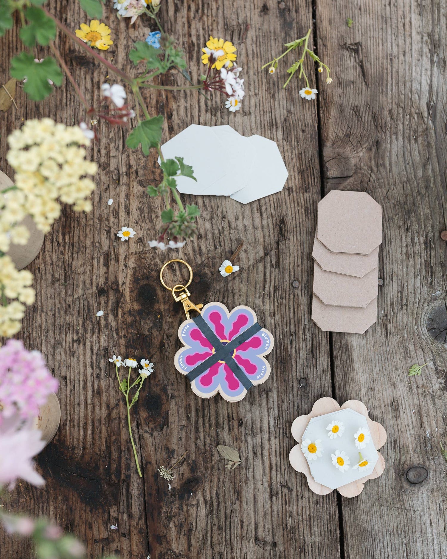 Attached to a lobster-claw Keyring, a pocket flower press that is a perfect size to press and dry flowers on the go. Flower-shaped in pink qnd yellow.. Strong elastic bands, 5 sheets of corrugated card and 8 sheets of sugar paper to ensure good pressing. 