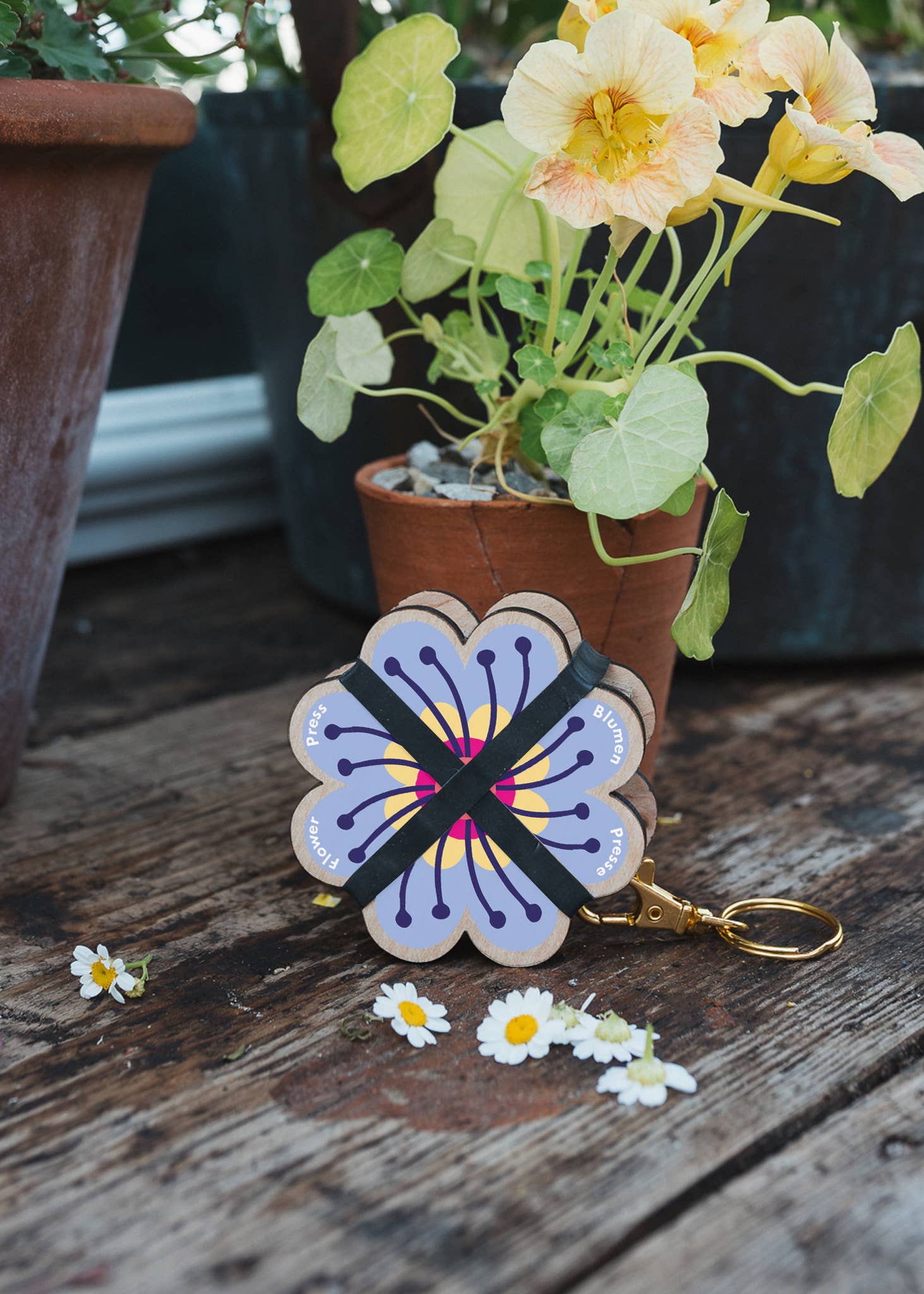 Attached to a lobster-claw Keyring, a pocket flower press that is a perfect size to press and dry flowers on the go. Flower-shaped in pink qnd yellow.. Strong elastic bands, 5 sheets of corrugated card and 8 sheets of sugar paper to ensure good pressing. 