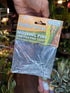 Hand holding a BetterGrow mossing pins package with a plastic bag.