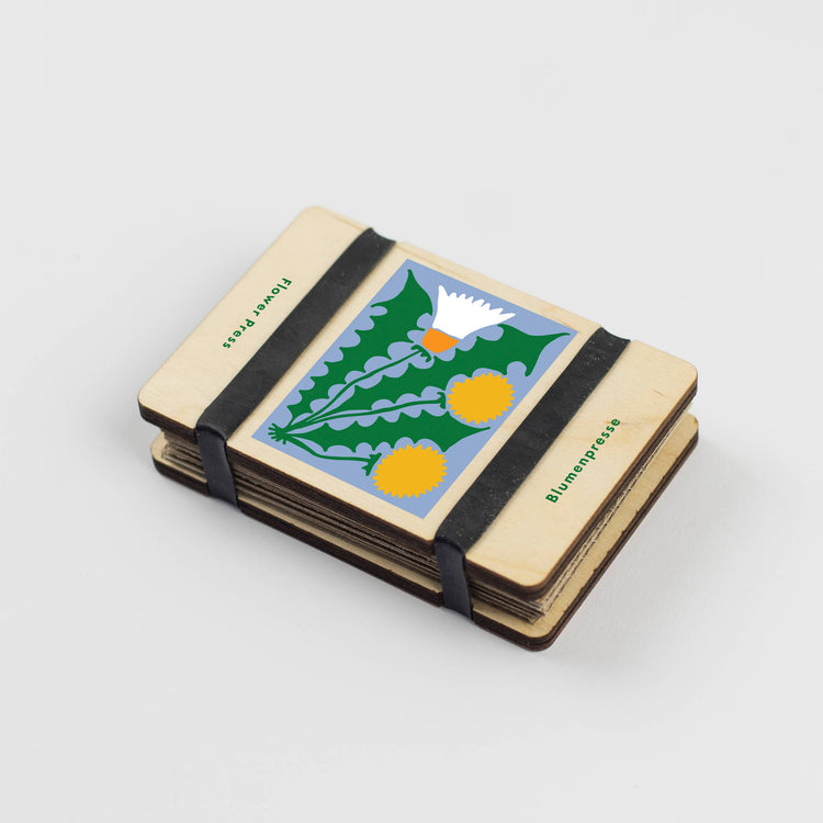 Pocket flower press that is a perfect size to press and dry flowers on the go. Blue, yellow and green dandelion print. Strong elastic bands, 5 sheets of corrugated card and 8 sheets of sugar paper to ensure good pressing. 