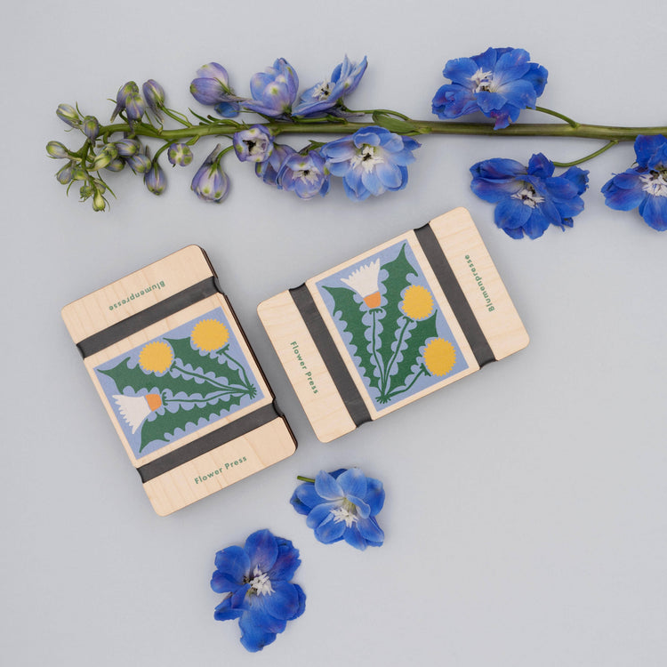 Pocket flower press that is a perfect size to press and dry flowers on the go. Blue, yellow and green dandelion print. Strong elastic bands, 5 sheets of corrugated card and 8 sheets of sugar paper to ensure good pressing. 