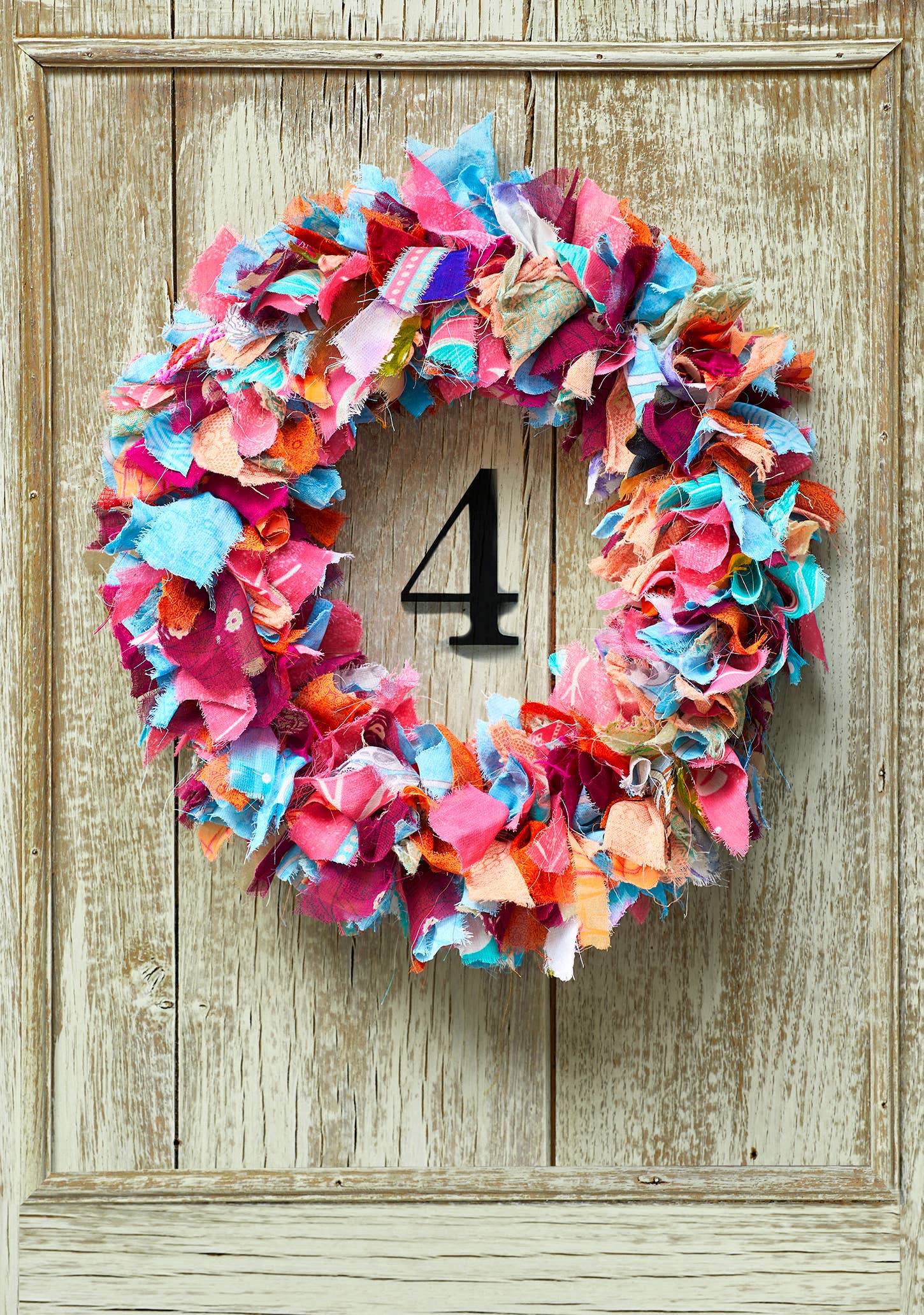 Colorful fabric wreath with number 4 on a wooden door