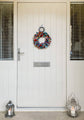 White door with a colorful wreath and lanterns on either side.