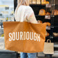 Person holding a brown tote bag with &
