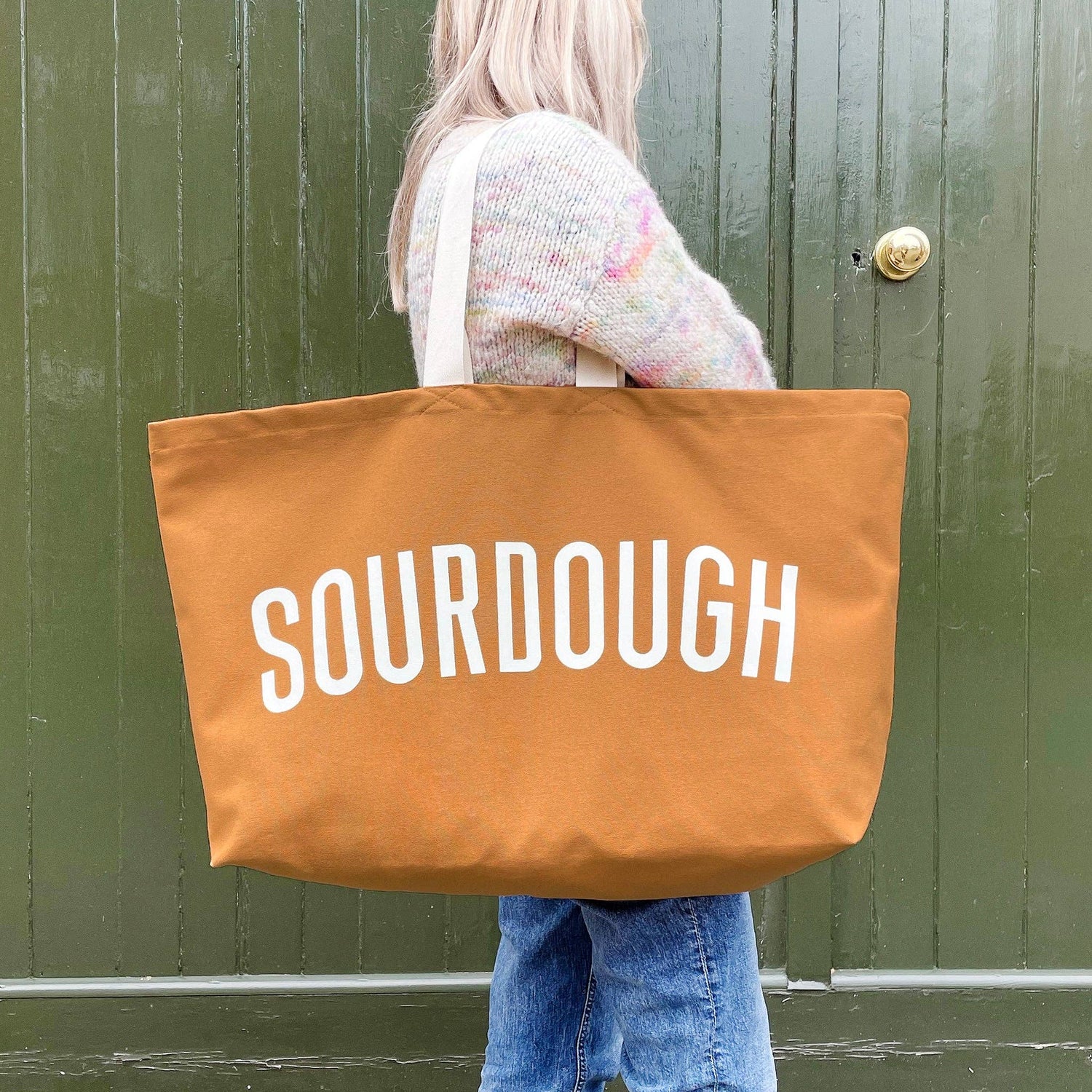 Person holding a large brown tote bag with &