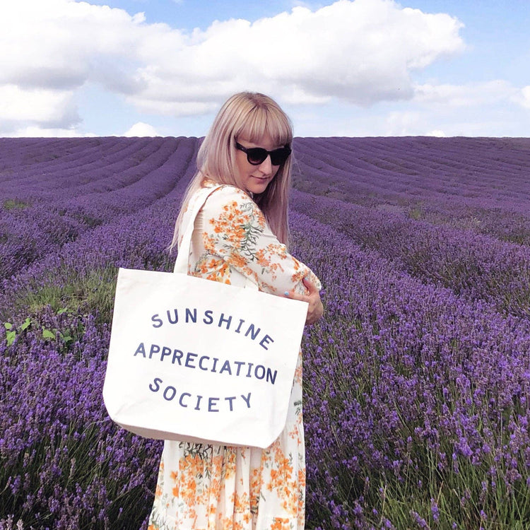 Person Wearing a Big Canvas Tote Bag with ‘Sunshine Appreciation Society’ Text on a Lavender Field Background