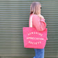 Person Carrying a Bright Pink Canvas Tote Bag with ‘Sunshine Appreciation Society’ text on Green Background
