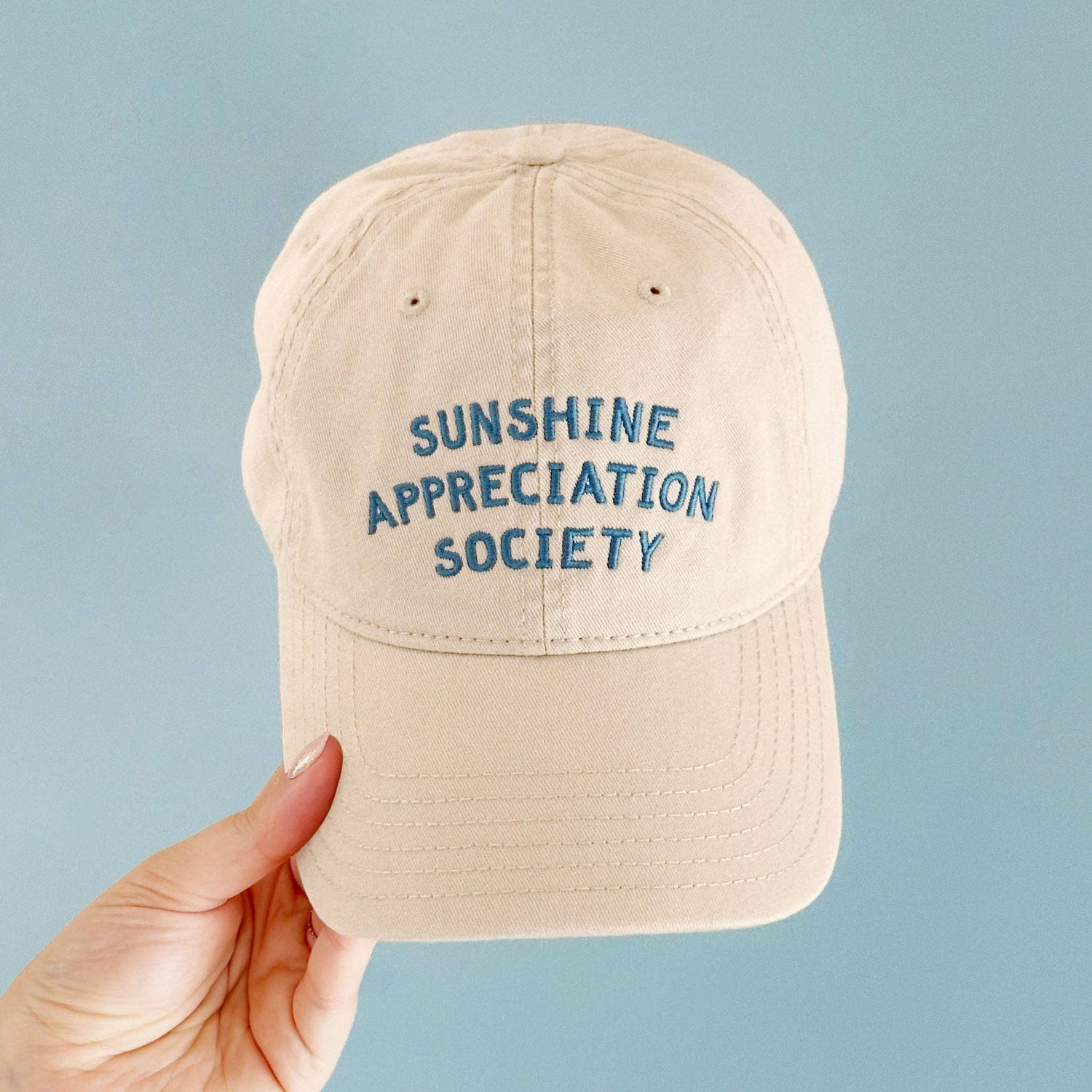 Off-White Cotton Baseball Cap with ‘Sunshine Appreciation Society’ text on a Neutral Background