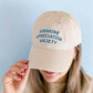 Person Wearing an Off-White Cotton Baseball Cap with ‘Sunshine Appreciation Society’ text on a Blue Background