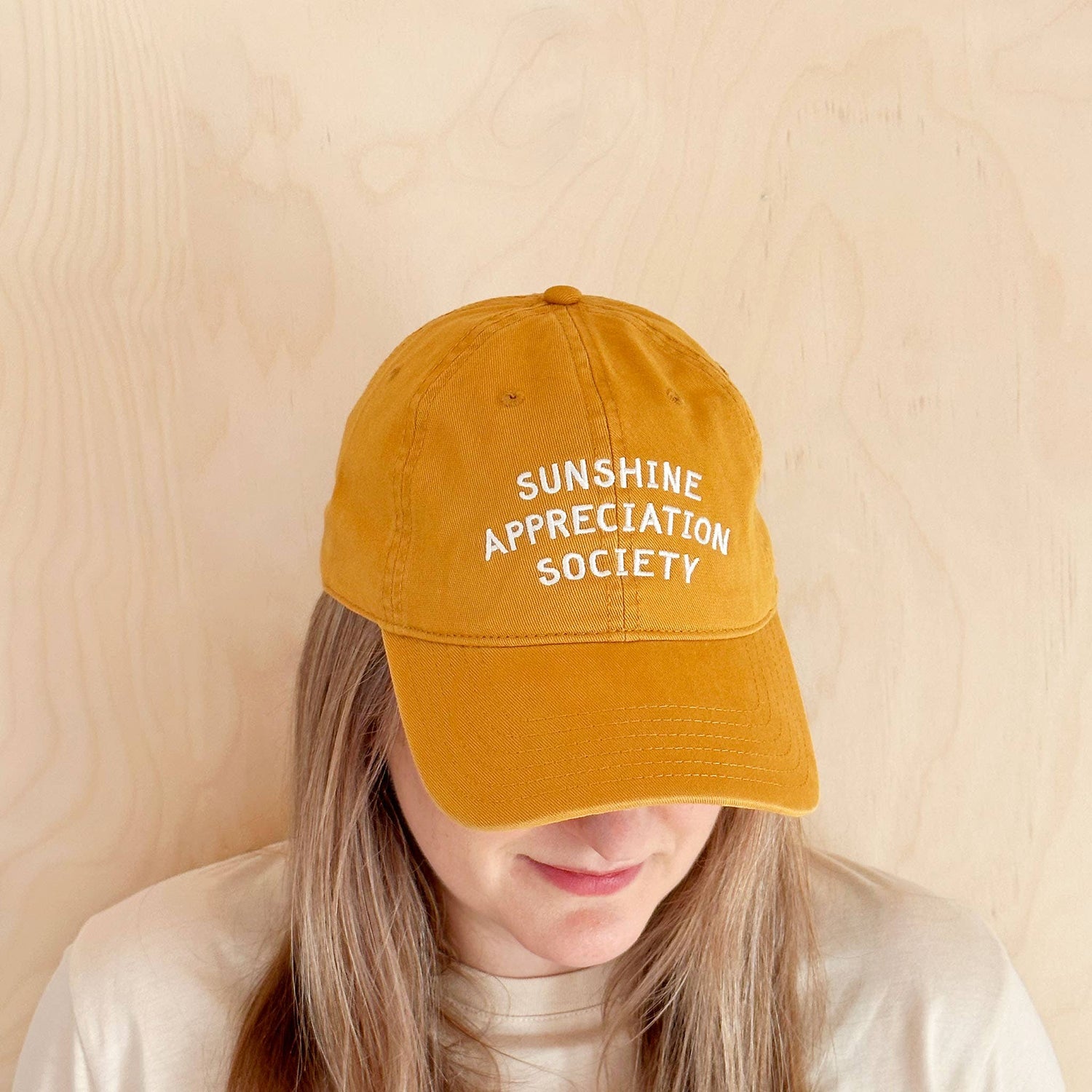 Person wearing a mustard yellow cap with &