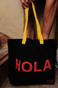 Black reusable canvas tote bag with yellow handles and bold red "Hola" and ‘Adiós’ graphic by The General Classification. Eco-friendly cotton shopping bag with modern minimalist design, ideal for everyday use, groceries, travel, and casual fashion.