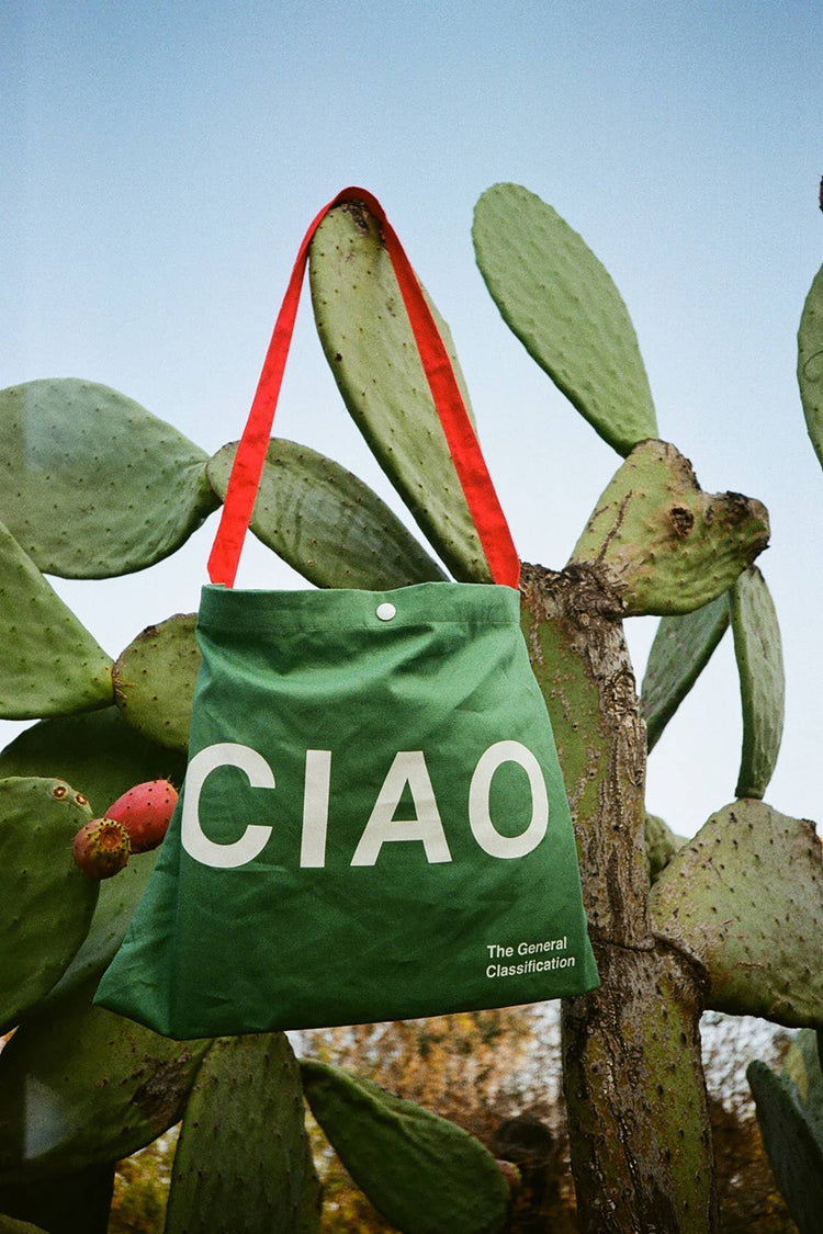 Green reusable canvas tote bag with red handles and bold white "Ciao" and ‘Arrivederci’ graphic by The General Classification. Eco-friendly cotton shopping bag with modern minimalist design, ideal for everyday use, groceries, travel, and casual fashion.