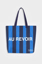 Blue and navy stripe reusable canvas tote bag with navy handles and bold white "Bonjour" and ‘Au Revoir’ graphic by The General Classification. Eco-friendly cotton shopping bag with modern minimalist design, ideal for everyday use, groceries, travel, and casual fashion.