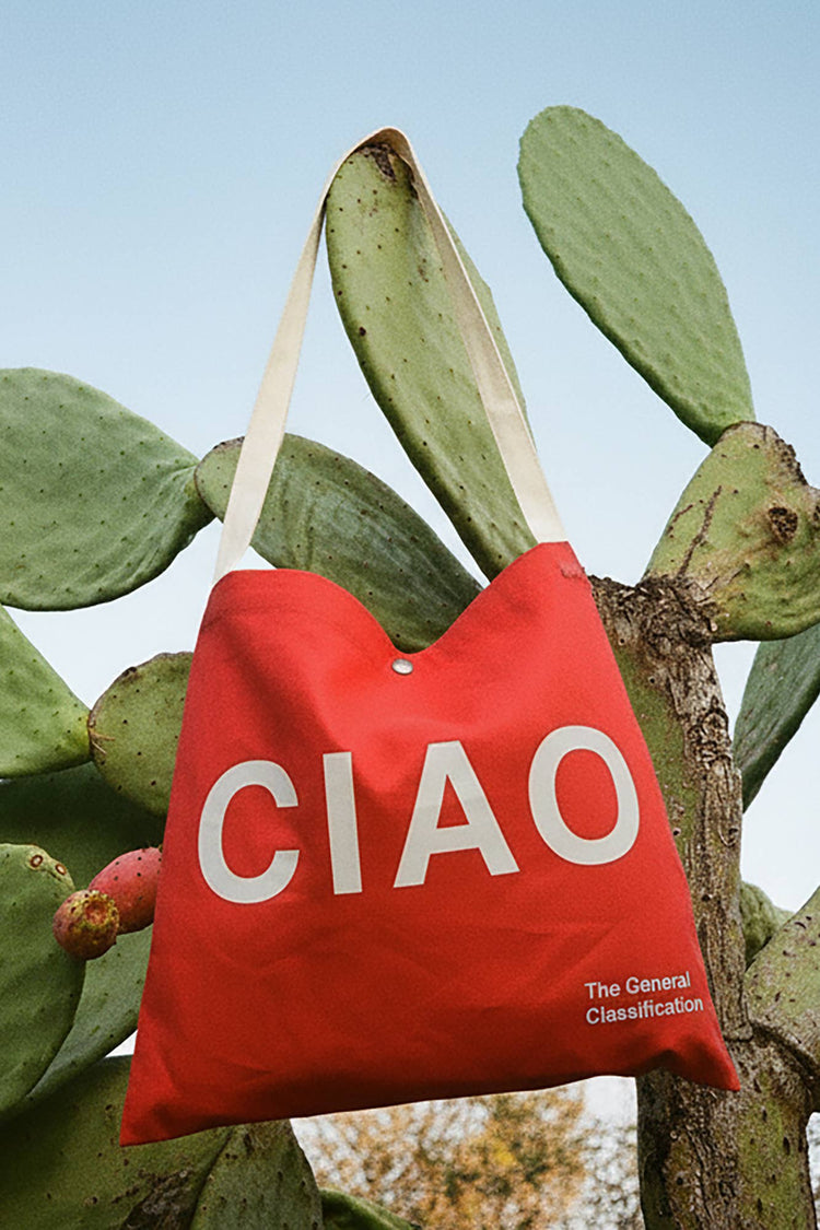 Red reusable canvas tote bag with white handles and bold white "Ciao" and ‘Arrivederci’ graphic by The General Classification. Eco-friendly cotton shopping bag with modern minimalist design, ideal for everyday use, groceries, travel, and casual fashion.