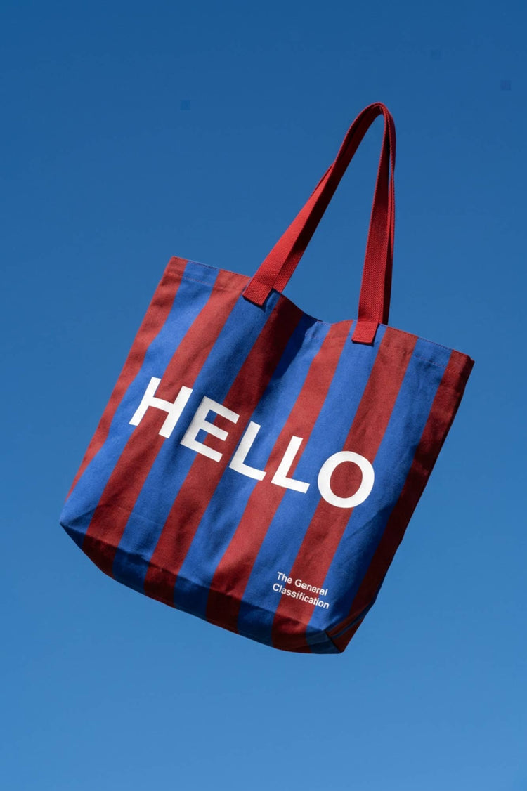 Red and navy stripe reusable canvas tote bag red handles and bold white "hello" and ‘goodbye’ graphic by The General Classification. Eco-friendly cotton shopping bag with modern minimalist design, ideal for everyday use, groceries, travel, and casual fashion.